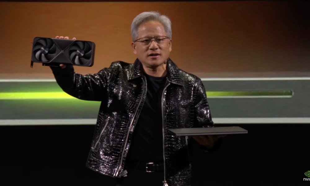 Nvidia CEO Jensen Huang holding an RTX 50 GPU and a laptop.